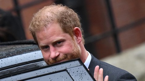Britanski Princ Harry stopa v črn SUV in drži roko na vratih ter gleda stran, približano.